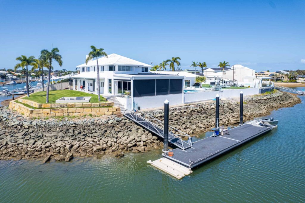 Waterfront house with white roof on rocky shoreline in SEQ.
