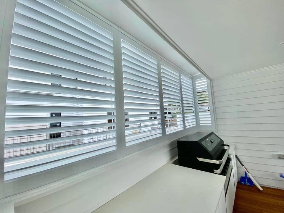 Bright room with shutters, white counter, and dark wood floor.