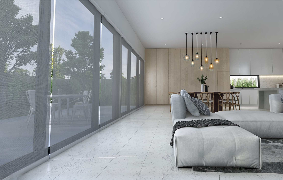 Modern open-plan living room with large floor-to-ceiling windows, grey sectional sofa, dining area, pendant lights, and a view of a patio with outdoor furniture.