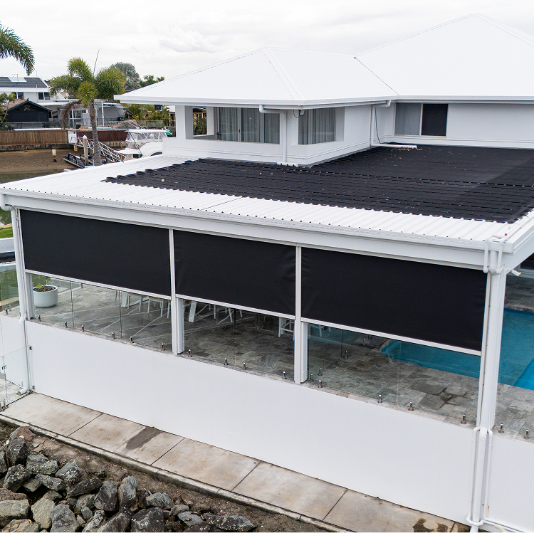 Modern two-story white house with a covered patio featuring three large black retractable blinds, glass barriers, and a view of the pool area.