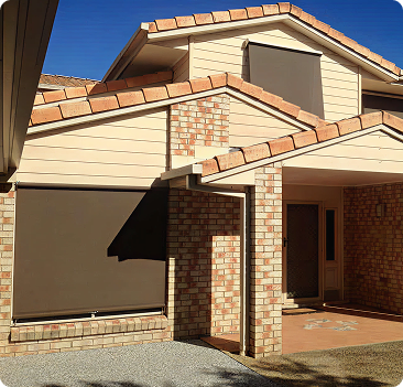 A two-story house with brick and beige siding has brown outdoor blinds covering its windows and a paved entrance area under a tiled roof.