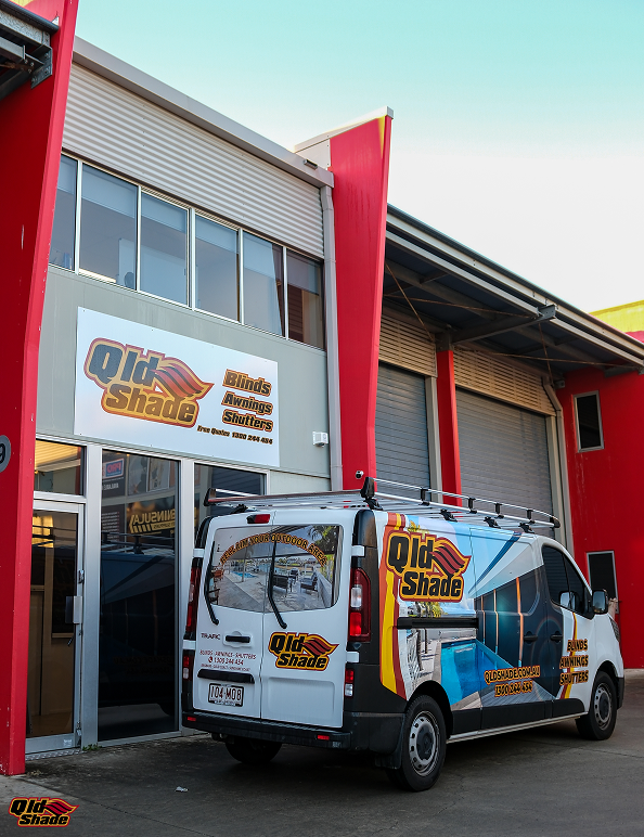 A van with “QLD Shade” branding is parked outside a commercial building with matching signage for blinds, awnings, and shutters.