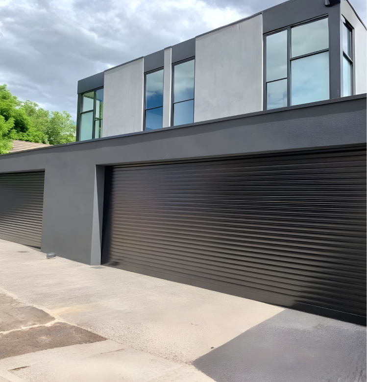 roller Modern two-story building with large windows and three closed black garage doors below, set against a partly cloudy sky and some greenery.
