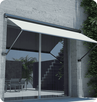 White retractable awning extended over a large glass sliding door on a modern building with outdoor furniture and greenery visible.