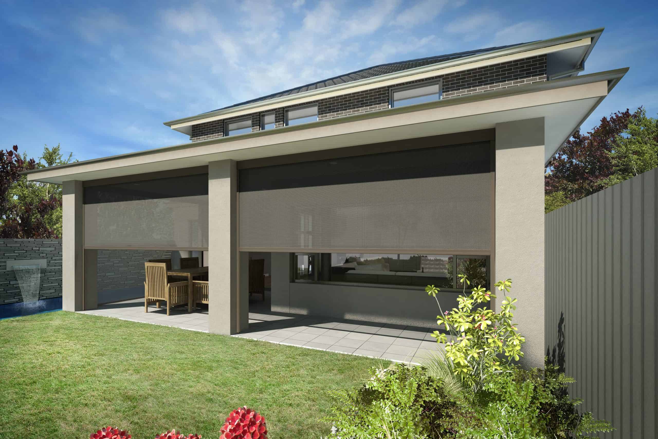 Modern two-story house with beige exterior, two large outdoor roller blinds covering a patio, outdoor dining set, and landscaped backyard with green lawn and flowering plants.