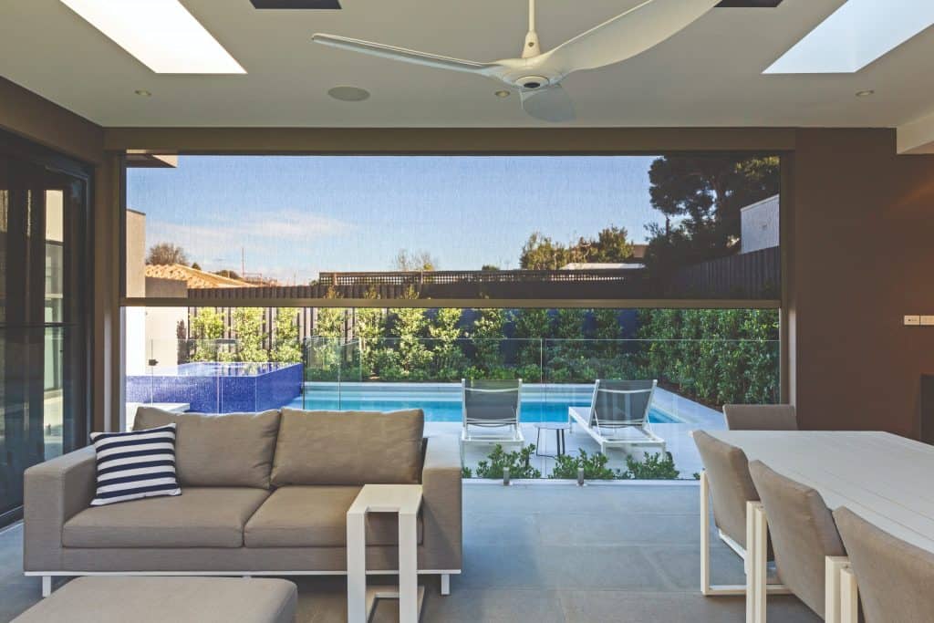 Modern living room with beige sofa, dining table, and pool view.